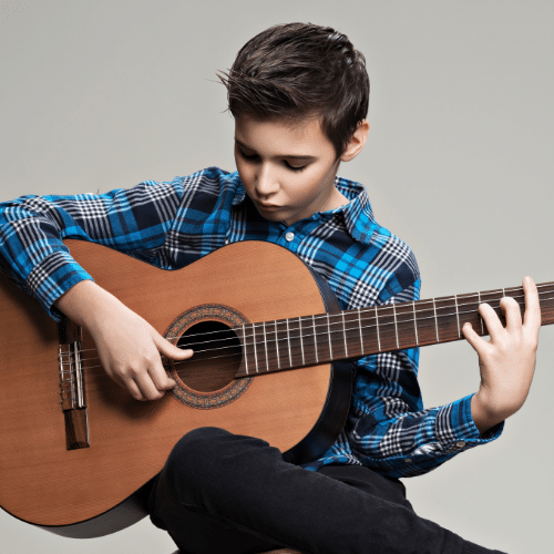 Een jongen die leert gitaar spelen.